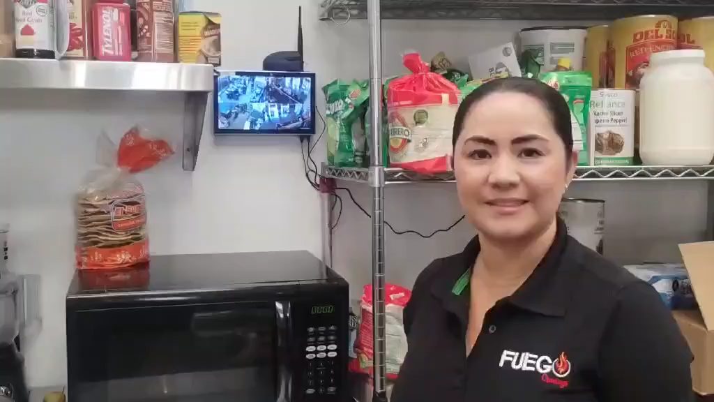 Clienta en la cocina de su restaurante con el monitor de cámaras detrás